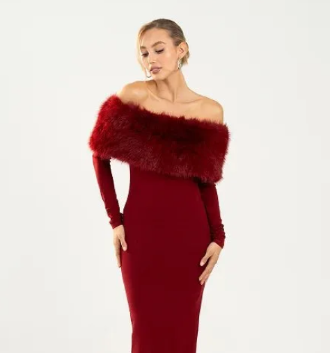 Woman wearing a burgundy off-shoulder dress with a fur shrug on a white background